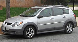 A gray compact car is parked on a street