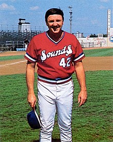 A man wearing a red baseball jersey with "Sounds" written across the chest in white.