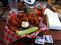 Buffalo wings with blue cheese dressing, served with lager beer.