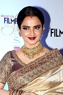 Rekha is looking at the camera and smiling.