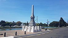 the paved side of the river an obelisk style monument sits on a plinth