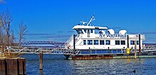 Ferry with NY Waterway is on its side, at a rusty floating dock with two aluminum gangways.