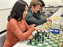 A female smiling as she plays chess.