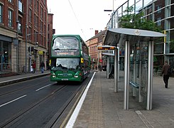 The tram stop looking south, as a bus passes through