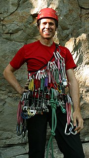 A rock climber carrying a large rack of equipment in preparation for their climb