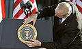 An aide affixes the presidential seal to the lectern before a 2012 speech