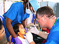 US Navy 040701-N-1050K-006 Dental Technician 3rd Class Nedra Jackson, left, comforts a 7-year-old Thai student while Capt. Michael McNamara administers a local anesthetic in preparation for a tooth extraction during a Dental Ci