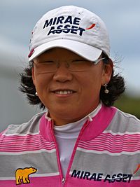 A brunette in a white hat with black lettering and gray and pink striped shirt