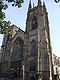 The end of an elaborate church with two towers, one flat-topped, the other with pinnacles