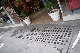 Purpled and patched vault lights outside the historic Chamberlin Hotel in Portland, Oregon. Grouting has been used to re-seal cracked glass jewels.