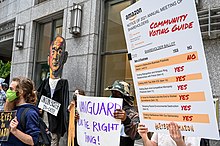 Demonstrators holding signs next to an effigy of Jeff Bezos