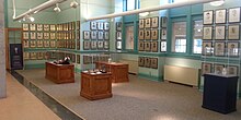 Large hallway with multiple display cases and plaques mounted on the walls