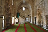 View of the mosque's prayer hall, with the mihrab on the left and the entrance portal on the right. The minbar is also visible past the mihrab.