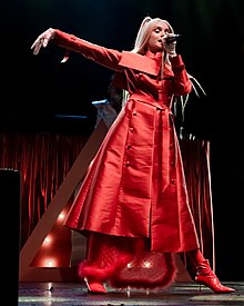 Poppy performing in a red dress and high heels