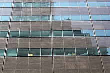 Facade detail, with horizontal strips of gray-green glass between spandrel panels of polished granite