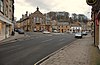 Junction near a busy town centre, with a town hall and nearby shops by the side of the road.