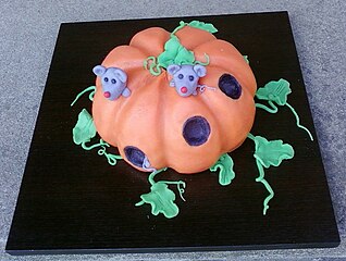 A cake decorated to look like a pumpkin with mice living in it