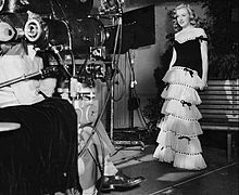 梦露在她的第一部电影合约期间穿着连衣裙面对电影摄影机拍摄宣传照。