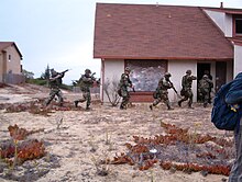 Group of soldiers enter into an abandoned residential building.