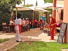 Trainees serving customers who are seated outside under umbrellas