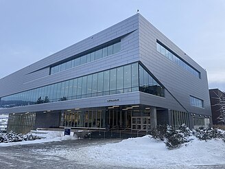 An image of the Commons building on the UBCO campus, a large 4-story gray and silver building with large windows.
