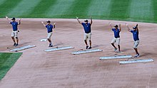 Wide shot of the ground crew on the baseball field dancing.