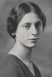 A young white woman with dark hair parted center and dressed to the nape