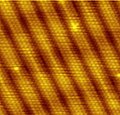 The characteristic reconstruction fringes on the (100) surface of gold are 1.44 nm wide[20] and consist of six atomic rows that sit on top of five rows of the crystal bulk. Image size is approximately 10 nm by 10 nm.