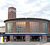 A brown-bricked building with a light blue strip over the doorway containing a darker blue sign reading "CHISWICK PARK STATION" in white letters