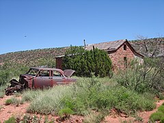 old stone schoolhouse with abandoned vehicle