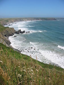 A broad bay surrounded by 50-metre-high cliffs, with waves breaking at their bases.