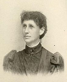 Portrait photograph of a middle-aged woman with her hair in an up-do, and wearing a high-collared blouse.