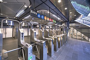 Turnstiles in the Fulton Center building, which is one of the station's entrances. There is a sign above the turnstiles, with the emblems of every route that serves the station.