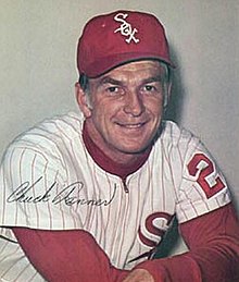 A man in a white baseball uniform and red cap