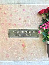 梦露的墓穴，摄于2015年。墓碑上写着“玛丽莲·梦露，1926-1962”。 坟墓表面覆盖着游客留下的口红印，旁边的花瓶放着粉红色与红色的玫瑰。