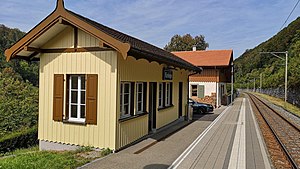 Yellow single-story building with gabled roof next to a single platform