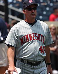 A man in a gray baseball uniform with "Minnesota" written across the chest in red letters and a navy blue cap with a red "M" on the front