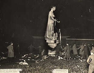 Black and white photograph of students dancing around Statue of Industry after tarring it