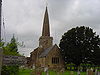 Stone building with spire surrounded by trees.