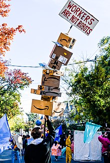 A marcher with a tall sign, held up by Amazon boxes