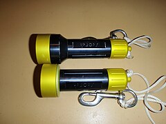 Two dive lights with the same LED; with lens upper and without lens lower. Both are switched on by screwing the back end cover clockwise to close an internal contact.