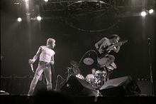 Roger Daltrey holding a microphone and Pete Townshend jumping on stage