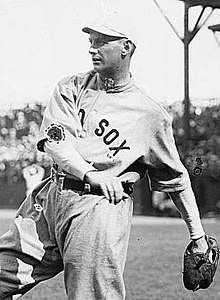 A man wearing a baseball uniform with "Red Sox" displayed on the chest caught in the midst of throwing a baseball