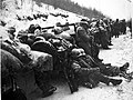 A convoy in the snow with men resting on the vehicles