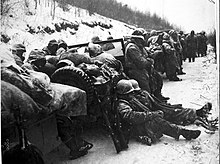 A convoy in the ．snow with men resting on the vehicles