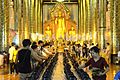 Inside the wihan of Wat Chedi Luang, money offerings are dropped into alms bowls during the festival