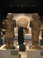 墨西哥城国立人类博物馆展出的科瓦特利奎（左）和维齐洛波奇特利（右）石雕。背景是阿兹特克日历石