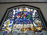 The Battle of Hastings (1066) as depicted on a stained glass window over the main entrance. The French phrase (l'action continue ... avec fureur) translates to "the battle rages on".