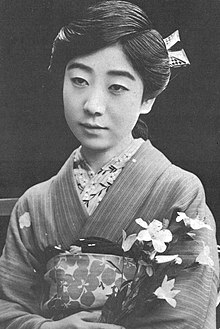 A young Japanese woman wearing a kimono embellished with flowers