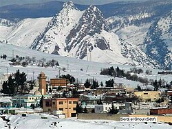Photograph of the town surrounded by snow with S snowy mountain in the background
